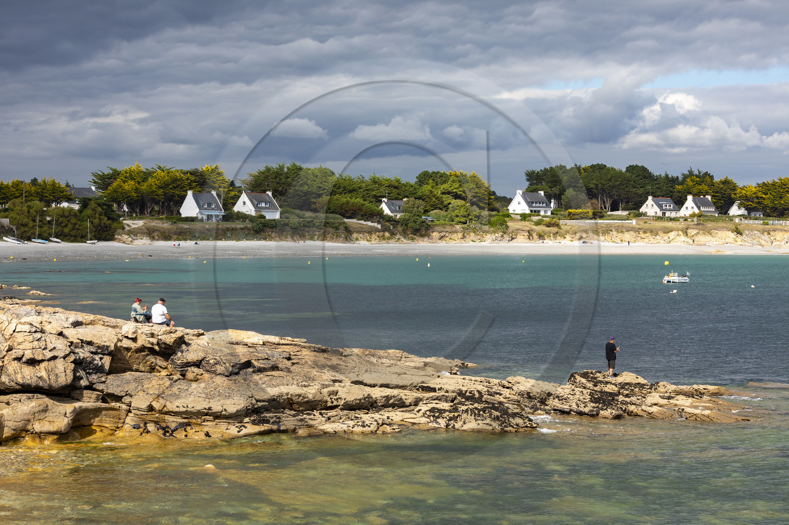 Pêcheur sur la pointe de Kerjean sur la commune de Trégunc. En arrière-plan, la plage de Kersidan